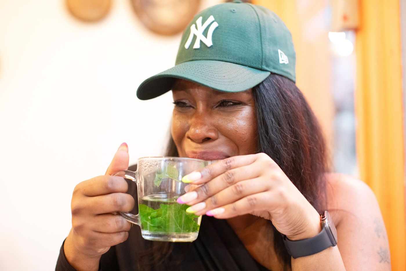 Woman in a baseball cap holding a green drink in the sun – personal branding photography by wo0, UK