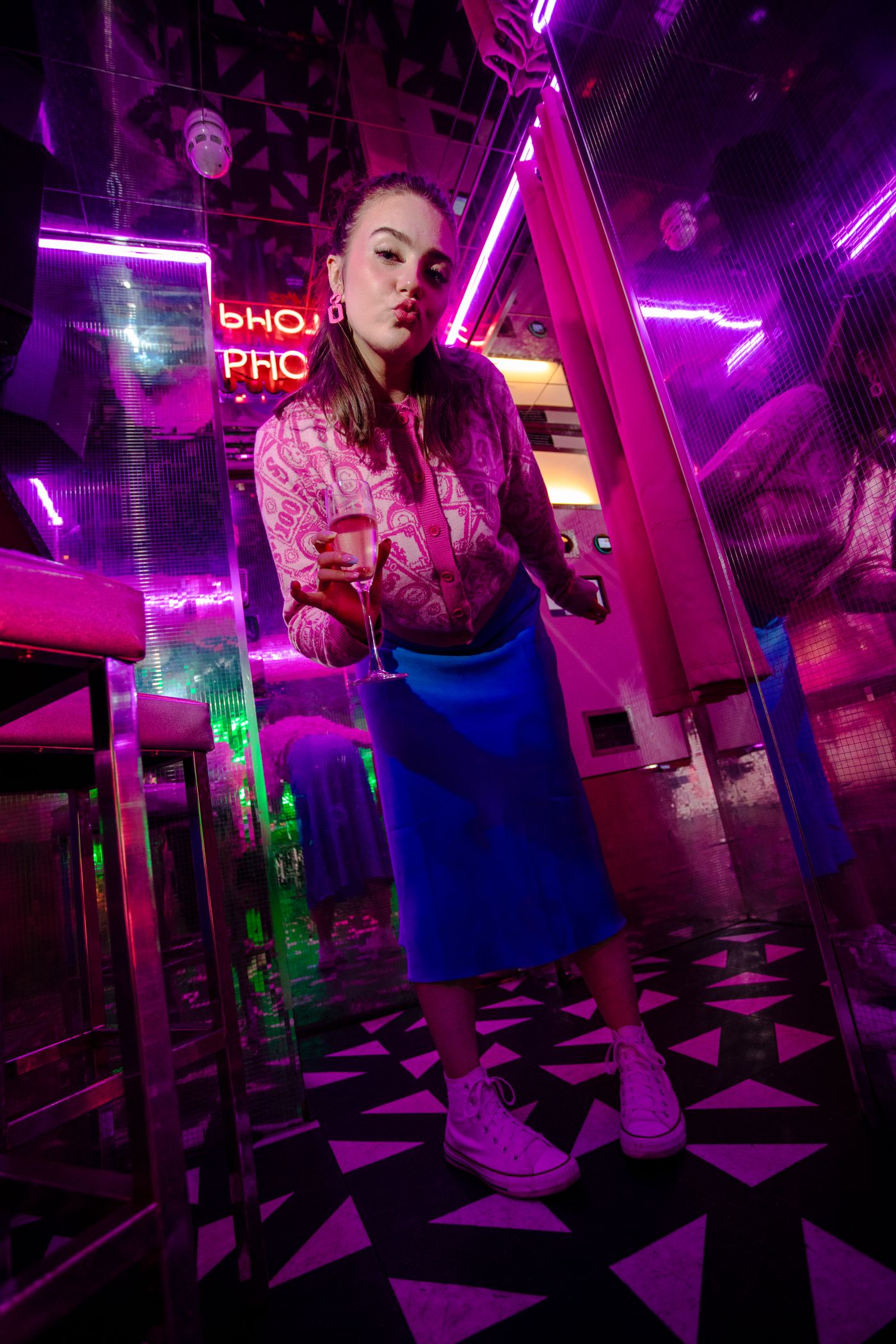 Woman standing in a bar lit with pink and purple neon – brand photoshoot by wo0