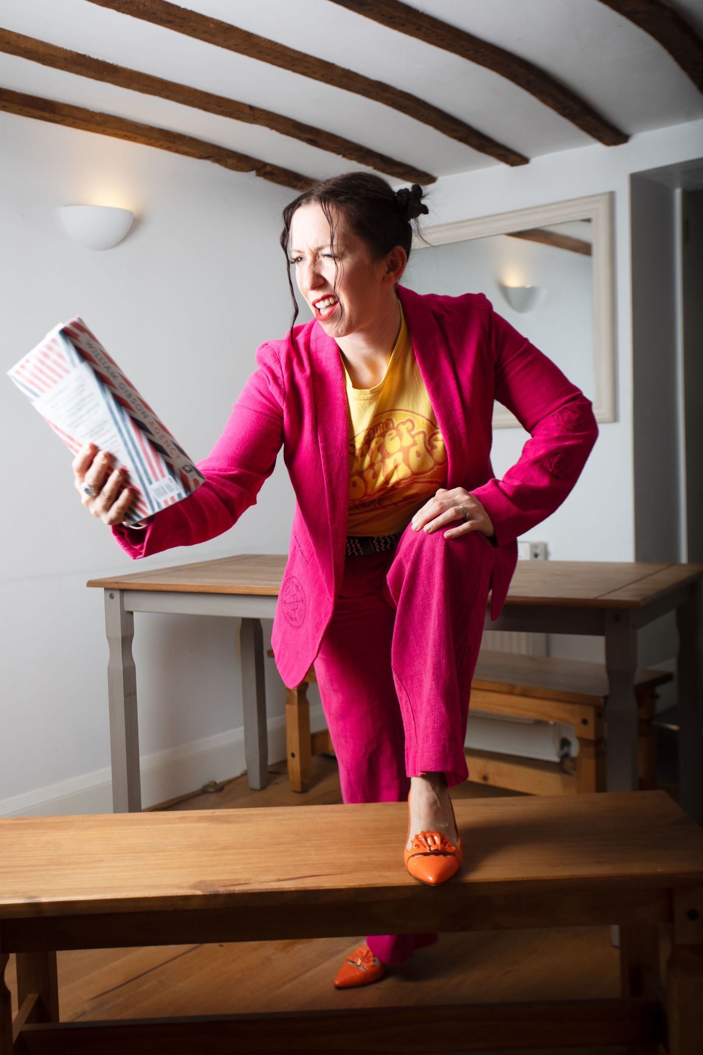 Woman in a pink suit holding a magazine and standing on a wooden bench – personality branding shoot by wo0