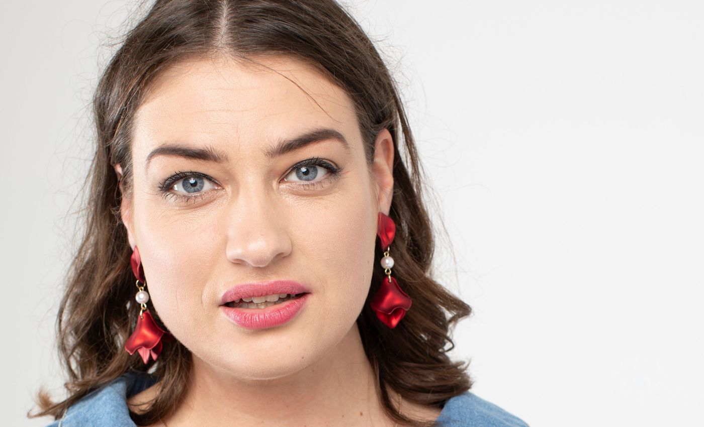 Headshot on a white background, blue top and red statement earrings – headshot photography by wo0, UK